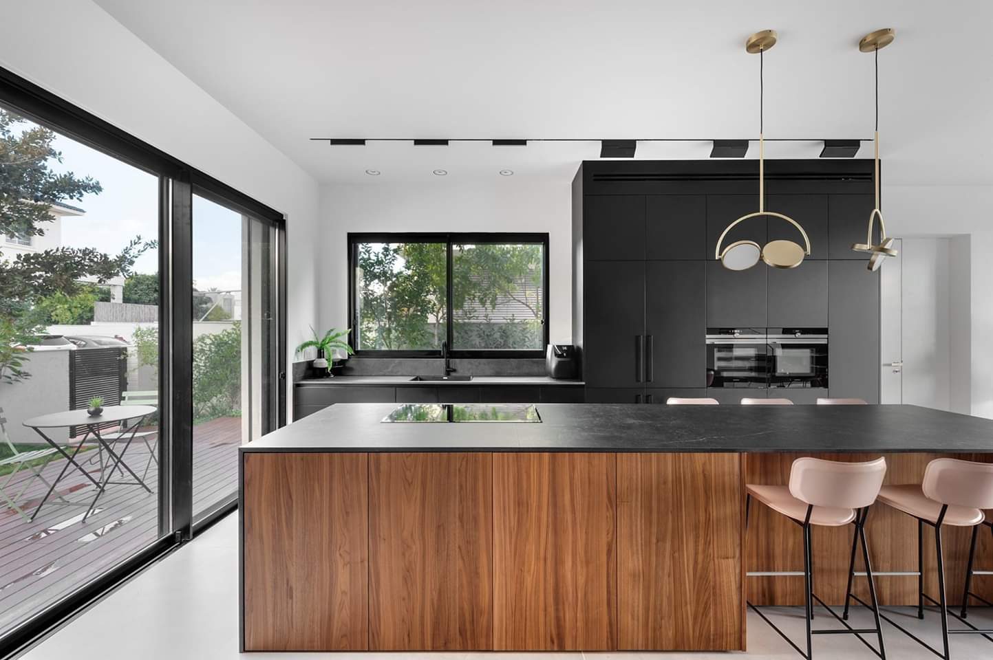 Walnut kitchen island lit by full-height glazing